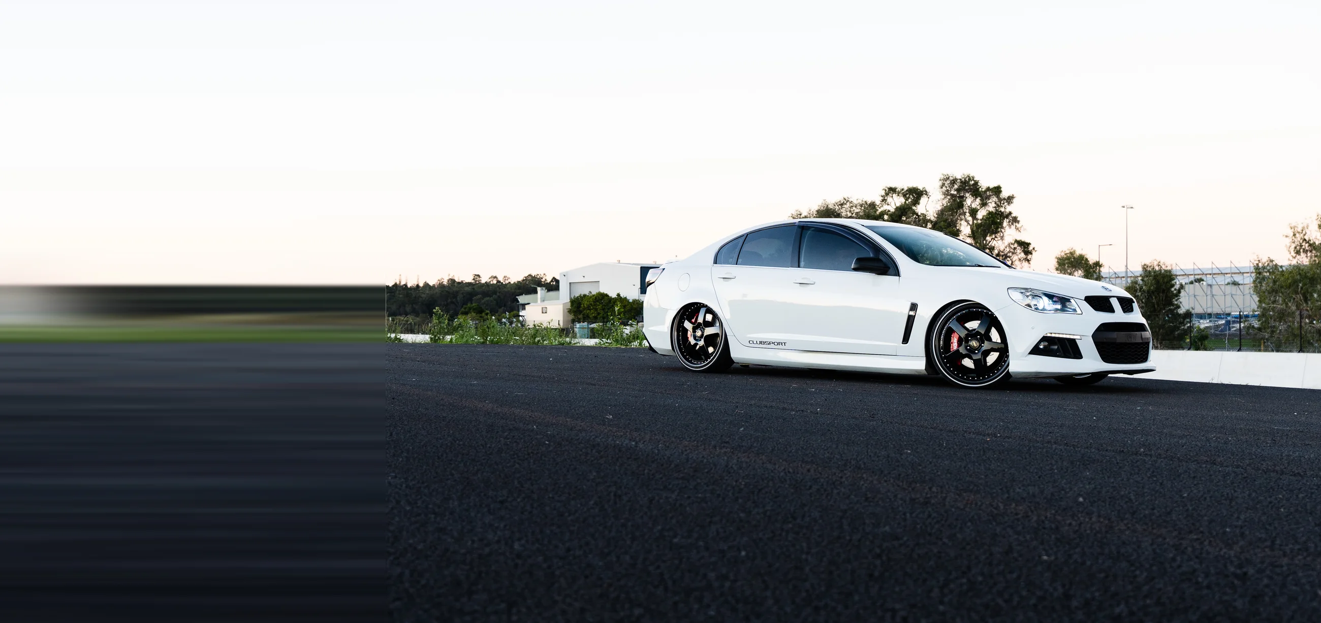 Pearl-white HSV GTS ClubSport, low stance front three-quarter on dark asphalt.